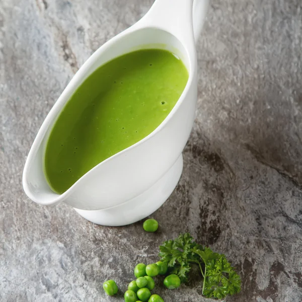 Bezelye çorbası püresi beyaz bir tureen içinde. Taş kayrak arka plan. Meydanı
