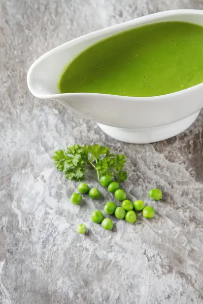 Bezelye çorbası püresi beyaz bir tureen içinde. Taş kayrak arka plan