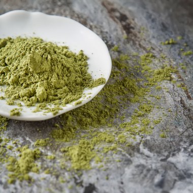 Küçük beyaz tabakta Matcha çay. Gri arka plan. Üstten Görünüm. SQ