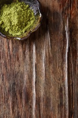 Matcha çay bir küçük kahverengi plaka kuru. Koyu ahşap arka plan. Sayfanın Üstü
