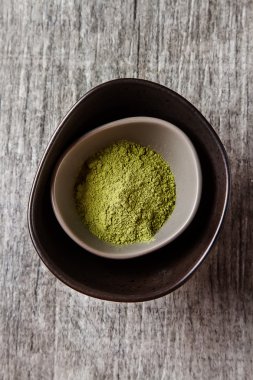 Matcha çay bir küçük kahverengi plaka kuru. Gri ahşap arka plan. Sayfanın Üstü