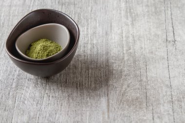 Matcha çay bir küçük kahverengi plaka kuru. Gri ahşap arka plan