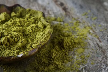Matcha çay bir küçük kahverengi plaka kuru. Koyu seramik arka plan