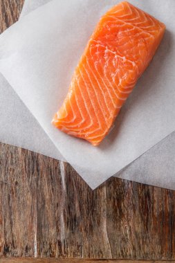 Bir parça taze somon beyaz kagit üzerinde. Koyu ahşap backg