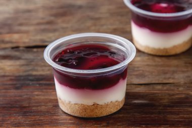 Hazır berry cheesecake plastik bir tencerede. Koyu ahşap arka plan.
