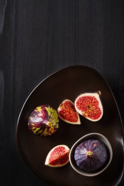 Bir plaka üzerinde sulu olgun incir. Koyu ahşap arka plan. Üstten Görünüm