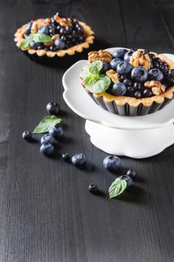 Ev yapımı yaban mersini tart, ceviz ve koyu ahşap masa nane. F