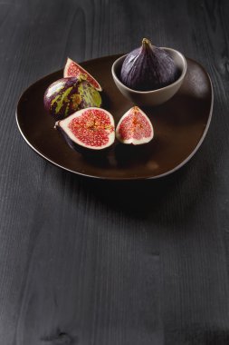 Bir plaka üzerinde sulu olgun incir. Koyu ahşap arka plan