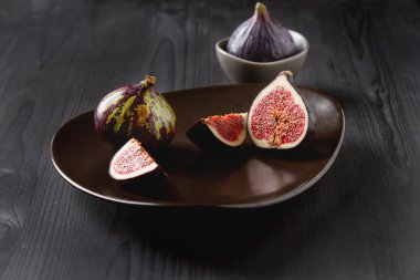 Bir plaka üzerinde sulu olgun incir. Koyu ahşap arka plan