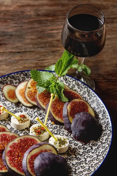 Higos jugosos maduros en un plato con queso de cabra y licor. Madera —  Fotos de Stock