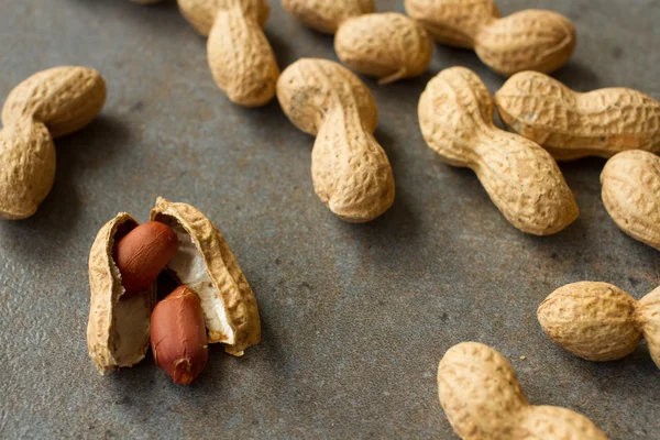 Peanuts in the skin and brushed on a gray background — Stock Photo, Image