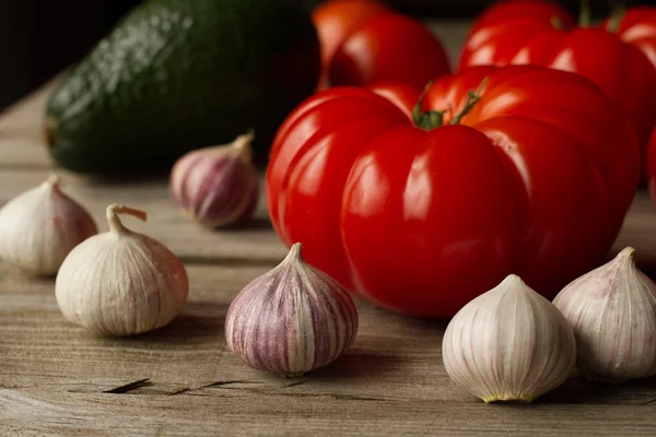 Tomato with avocado and garlic with dill. on wood background — Stock Image Tomato with avocado and garlic with dill. on wood background Stock Photo