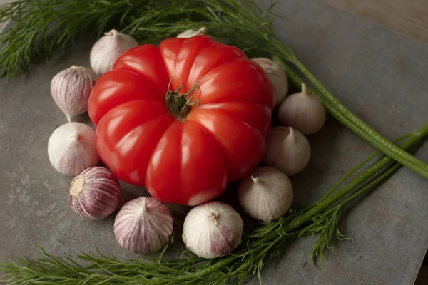 Tomato with avocado and garlic with dill. on wood background — Stock Image Tomato with avocado and garlic with dill. on wood background Stock Photo