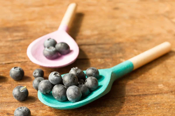 Blueberries and wooden spoon on a wooden tray — Stock Photo, Image