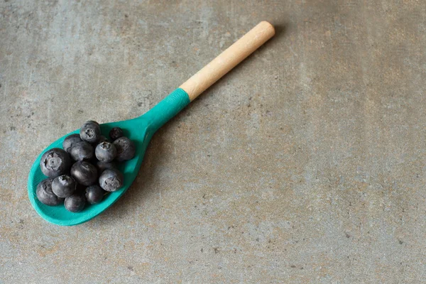 Blueberries and wooden spoon on a wooden tray — Stock Photo, Image