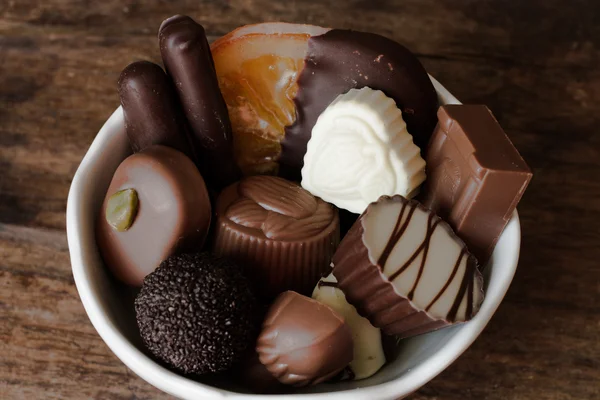 Belgische chocolade in een witte kom op een houten tafel — Stockfoto