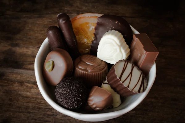 Belgische chocolade in een witte kom op een houten tafel — Stockfoto