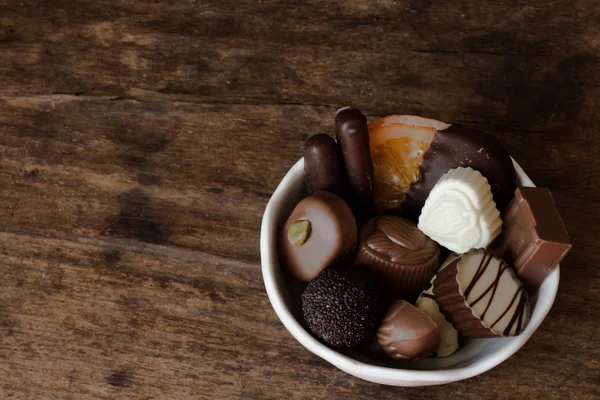 Belgische chocolade in een witte kom op een houten tafel — Stockfoto