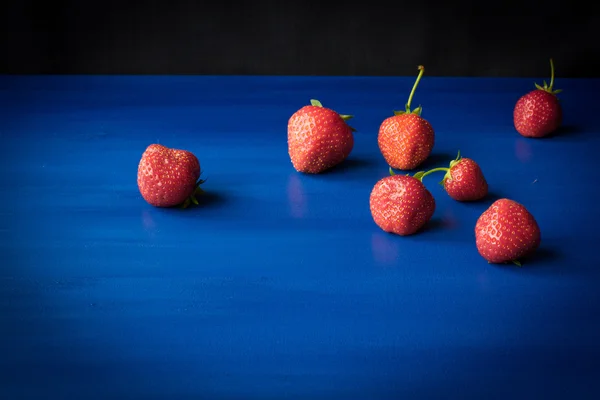Maturare fragole rosse su sfondo blu — Foto Stock