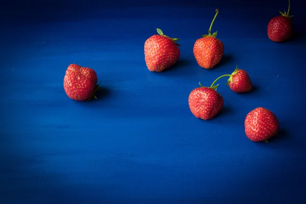 Maturare fragole rosse su sfondo blu — Foto Stock