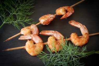 Siyah bir taş üzerine dereotu ile ızgara karides