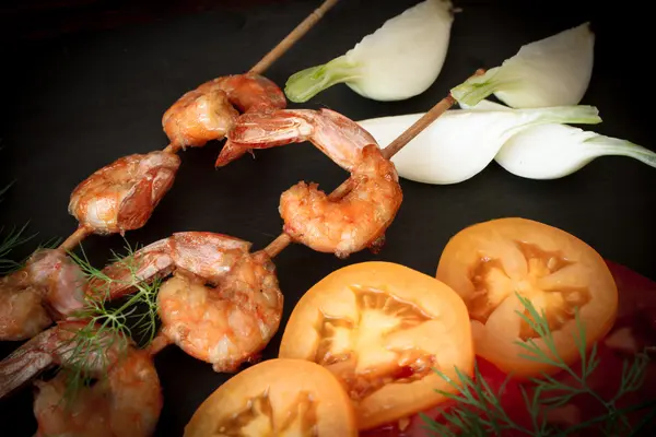 Grilled shrimp with dill tomatoes and onions on a black stone — 图库照片