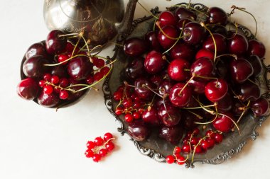 cherry with red currants in a bowl and a metal plate in oriental