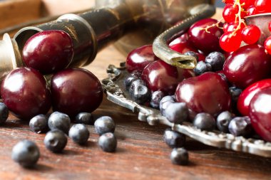 kiraz kırmızı kuş üzümü ve yaban mersini bir sürahi ve metal pl