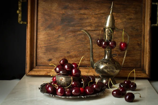 Cereza dulce con una jarra de metal y plato de estilo oriental —  Fotos de Stock