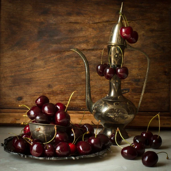 Cereza dulce con una jarra de metal y plato de estilo oriental —  Fotos de Stock