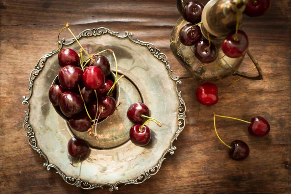 Cereza dulce con una jarra de metal y plato de estilo oriental —  Fotos de Stock