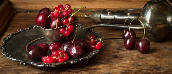 Cherry with red currants in a bowl and a metal plate in oriental — Stock fotografie