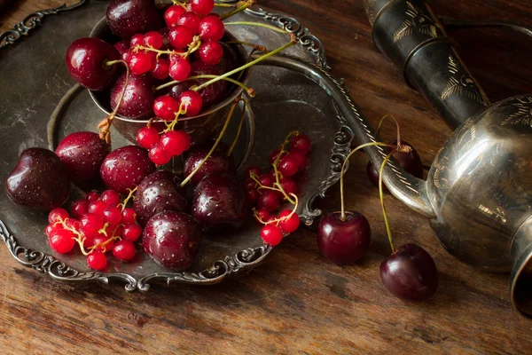 Cherry with red currants in a bowl and a metal plate in oriental — Stock fotografie