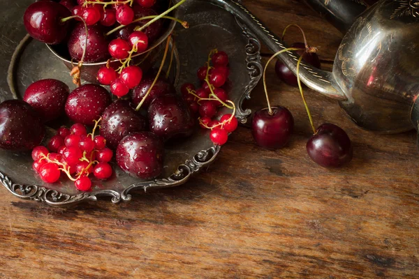 Cherry with red currants in a bowl and a metal plate in oriental — 图库照片