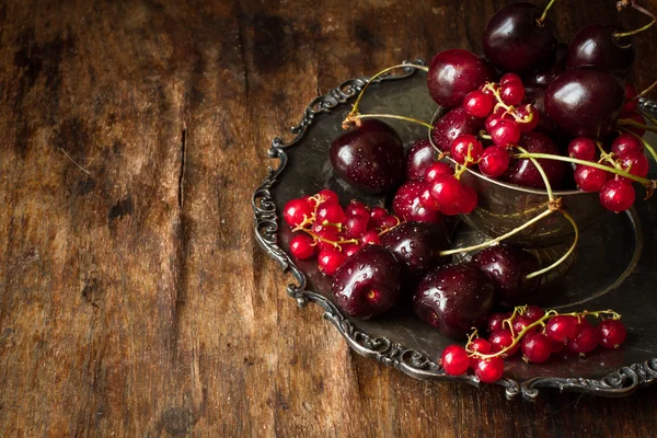 Cherry with red currants in a bowl and a metal plate in oriental — 图库照片