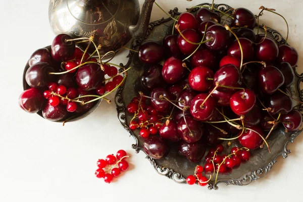 Cherry with red currants in a bowl and a metal plate in oriental — Stok fotoğraf