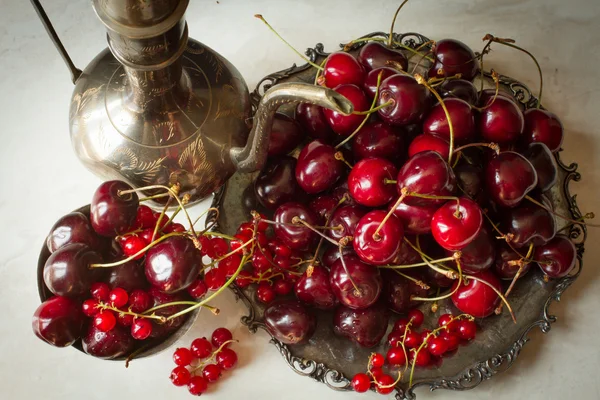 Cherry with red currants in a bowl and a metal plate in oriental — Stock fotografie