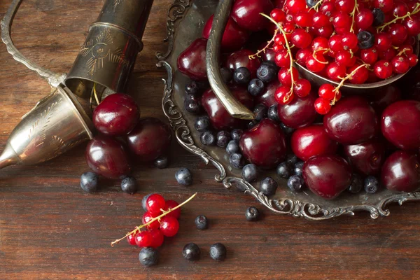 Cereza con grosellas rojas y arándanos en una jarra y un pl de metal —  Fotos de Stock