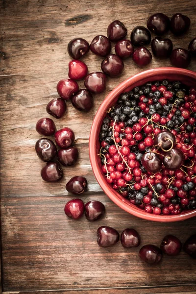 Cherry with red currants and blueberries in a red plate — Stock fotografie