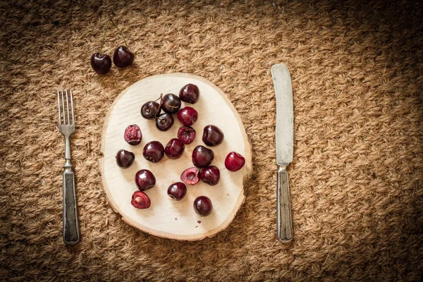 Cherry on a cut tree with old knife and fork — Stock fotografie