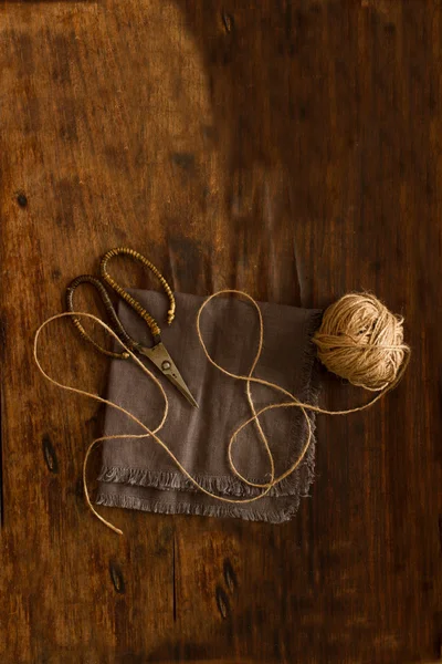 Scissors lying on linen fabric with a rope on a wooden backgroun — Stock Photo, Image