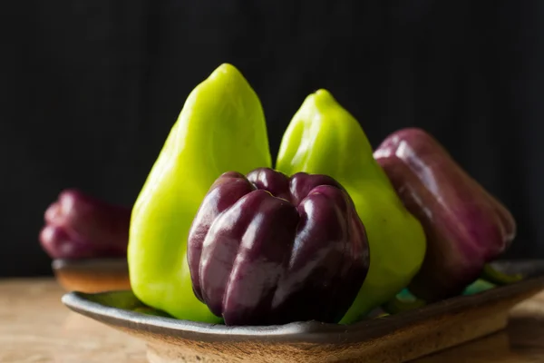 Pimientos púrpura y verde sobre un fondo de mármol —  Fotos de Stock