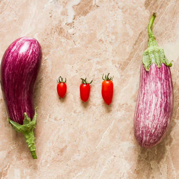 Berenjena madura y tomates cherry sobre una piedra de fondo amarillo —  Fotos de Stock