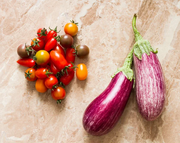 Berenjena madura y tomates cherry sobre una piedra de fondo amarillo —  Fotos de Stock