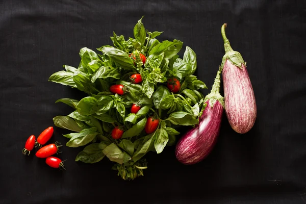 Albahaca verde con berenjena y tomates sobre fondo negro —  Fotos de Stock