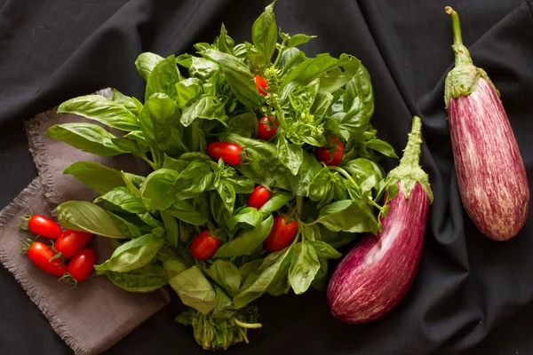 Albahaca verde con berenjena y tomates sobre fondo negro —  Fotos de Stock