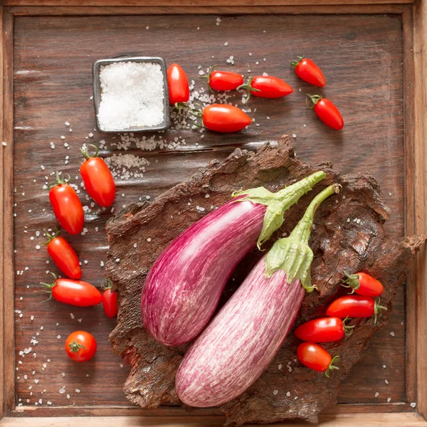 Berenjena madura con tomates y sal sobre un fondo de madera —  Fotos de Stock