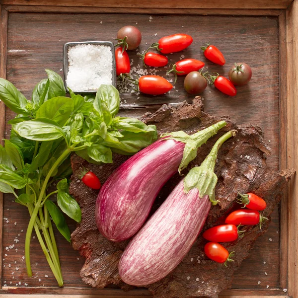 Berenjena madura con tomates y sal sobre un fondo de madera —  Fotos de Stock