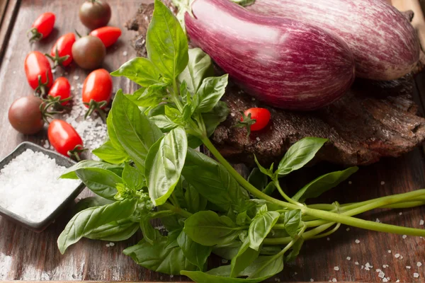 Ripe eggplant with tomatoes and salt on a wooden background — Stock Photo, Image