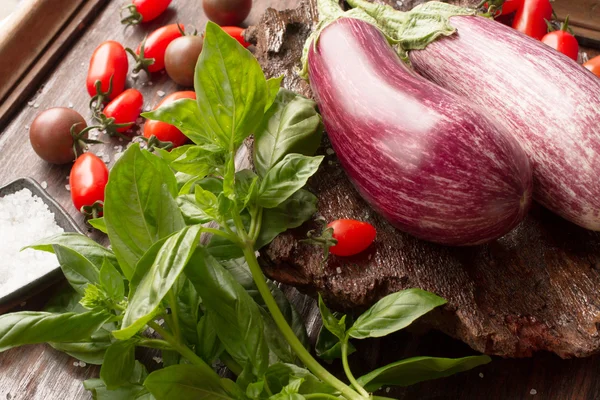 Berenjena madura con tomates y sal sobre un fondo de madera —  Fotos de Stock